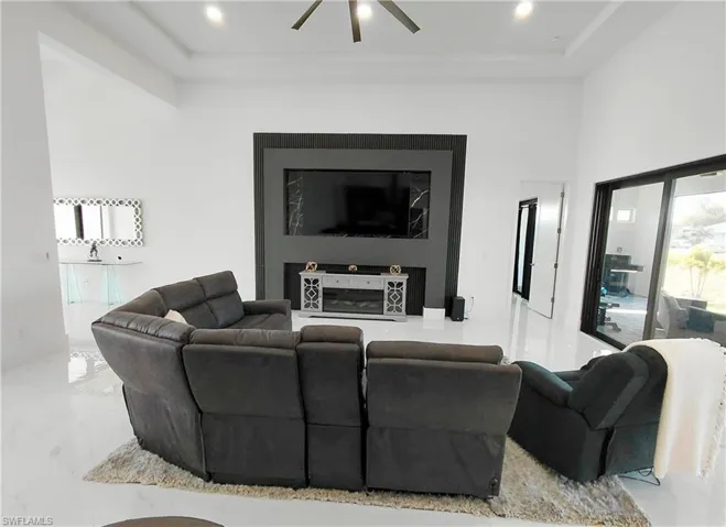 The property features an expansive living area with white walls and a white floor, illuminated by recessed lighting and a ceiling fan