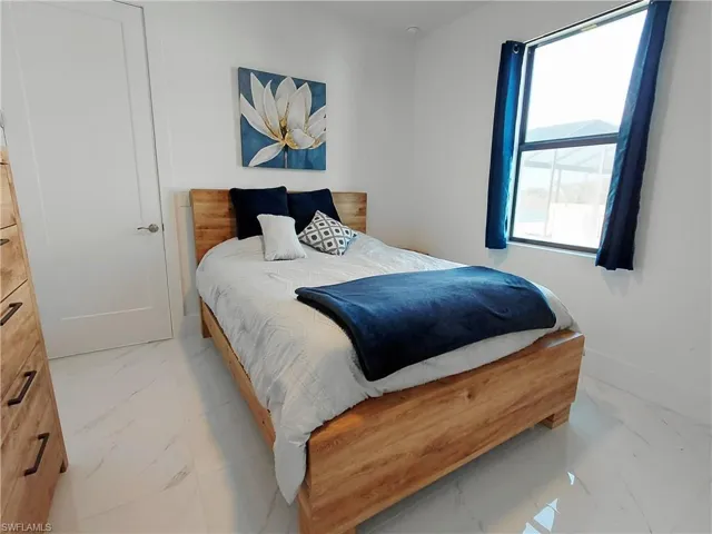 This room features white walls, a light wood bed frame, and white flooring with a subtle pattern