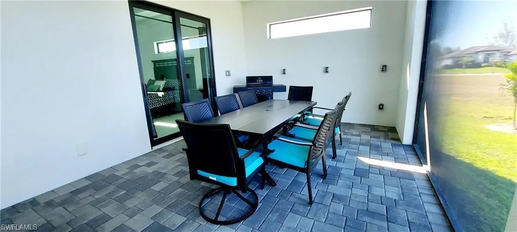 The property features an outdoor patio with paver flooring, a long rectangular table, and a built-in outdoor grill