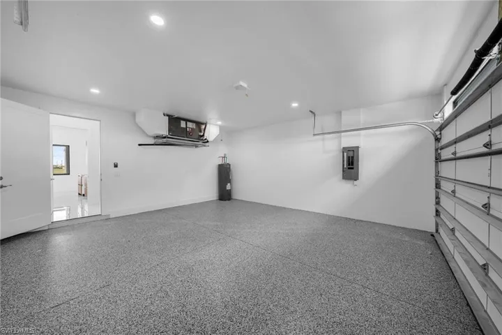 Spacious garage featuring a durable speckled epoxy floor, recessed lighting, and a roll-up garage door