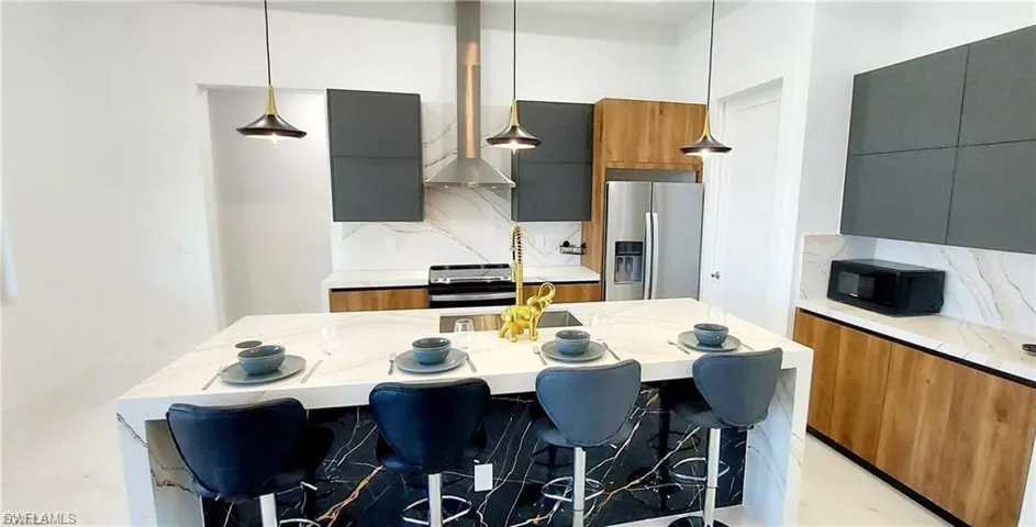 Modern kitchen featuring a waterfall island with a black and white marble finish, stainless steel appliances, and sleek cabinetry