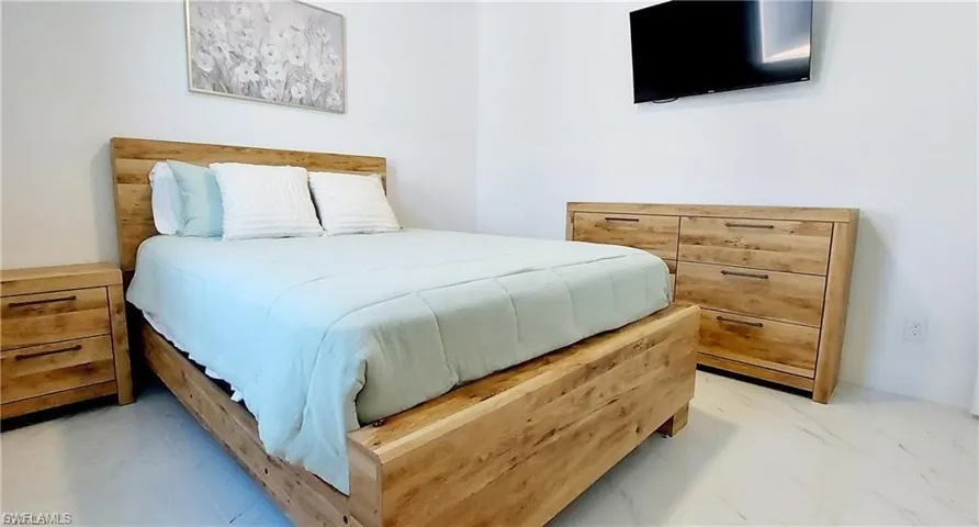 Guest Bedroom featuring white walls, light-colored flooring, and a window with natural light