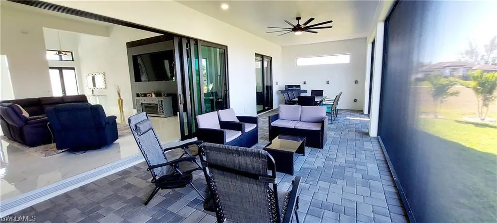 Expansive outdoor living area featuring paver flooring, a ceiling fan, and sliding glass doors
