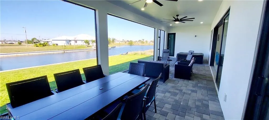 Expansive covered lanai featuring a paver floor, recessed lighting, and ceiling fans, with views of the canal and green space