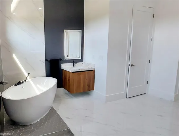 This bathroom features a contemporary freestanding bathtub, a floating wooden vanity with a marble countertop, and a large mirror