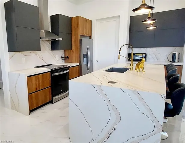 Contemporary kitchen featuring an island with a sink, pendant lighting, and a suite of stainless steel appliances