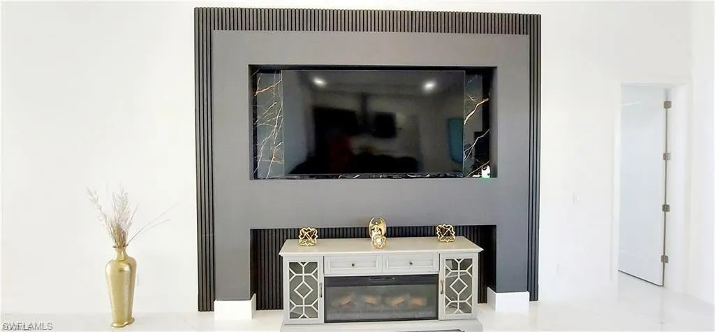 This living space features a stylish accent wall with a television niche and a built-in electric fireplace below
