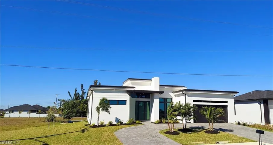 The property features a contemporary architectural style, a paver driveway, and a well-maintained lawn