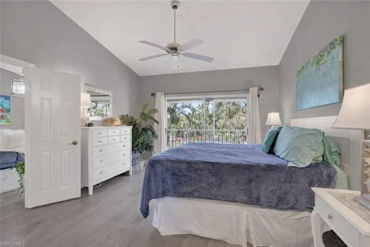 Bedroom with wood finished floors, access to outside, ceiling fan, and high vaulted ceiling