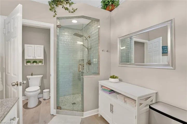 Full bath with vanity, a stall shower, and light wood-type flooring
