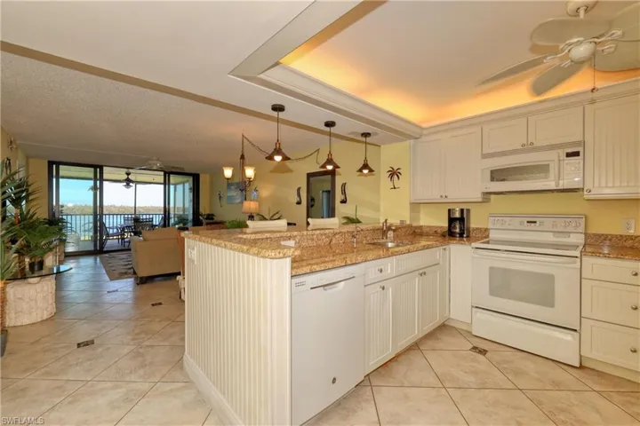 Kitchen featuring ceiling fan, white appliances, light tile patterned flooring, open floor plan, and floor to ceiling windows