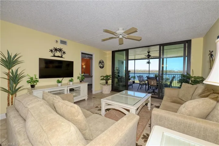 Living room featuring a wall of windows, a ceiling fan, a textured ceiling, and a sunroom