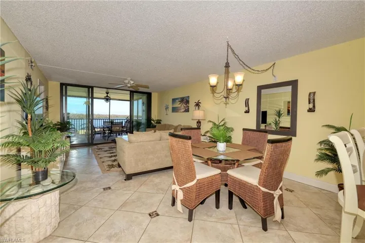 Dining area with a wall of windows, a textured ceiling, light tile patterned floors, a ceiling fan, and a chandelier