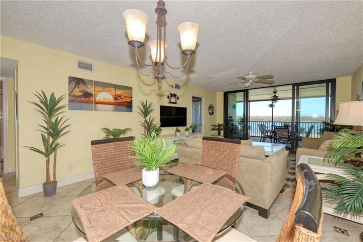 Tiled dining space with floor to ceiling windows, a textured ceiling, a chandelier, and ceiling fan