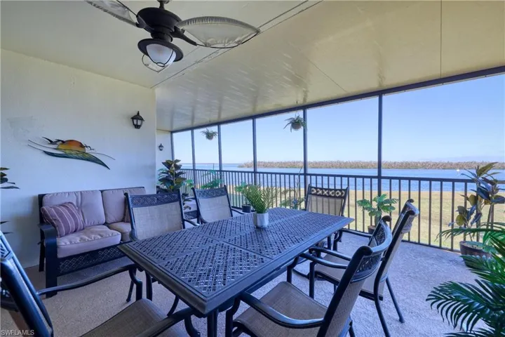 Sunroom / solarium featuring a water view, a ceiling fan, and outdoor dining area