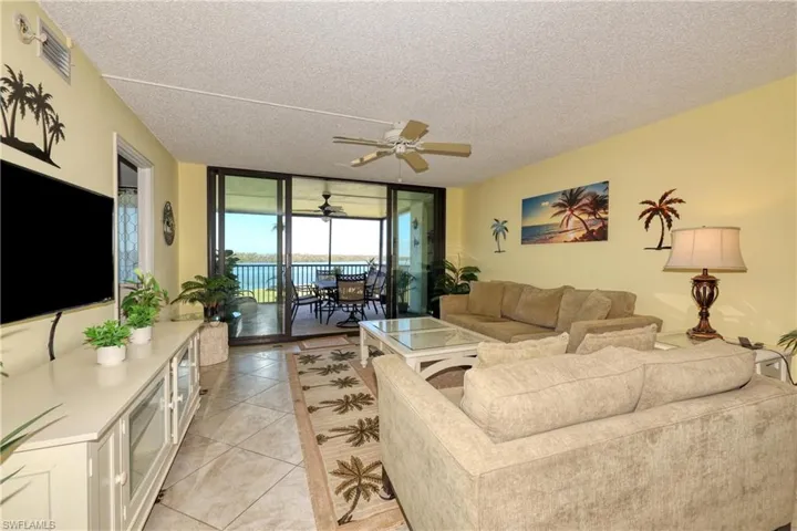 Living area featuring floor to ceiling windows, ceiling fan, a textured ceiling, and light tile patterned flooring