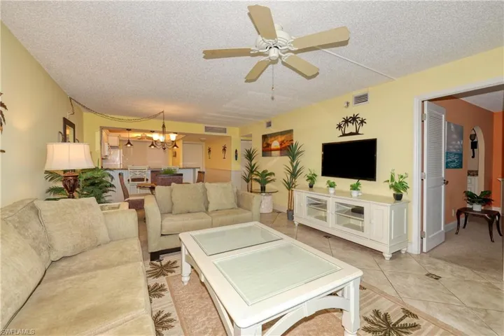 Living area featuring tile patterned flooring, a chandelier, a textured ceiling, and ceiling fan
