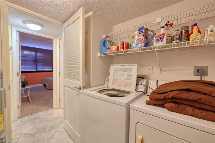 Laundry area featuring a textured ceiling, washer and dryer, and light tile patterned floors
