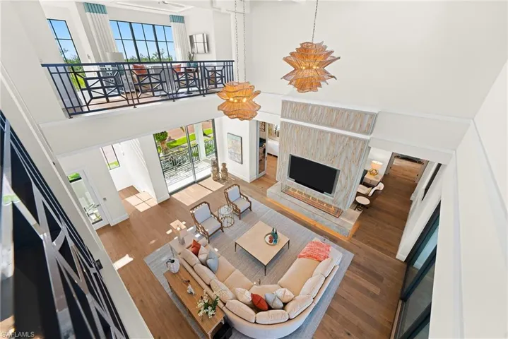 Living area with a towering ceiling, healthy amount of natural light, wood finished floors, and a premium fireplace