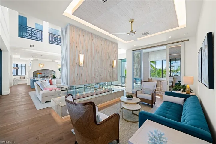 Living room with a raised ceiling, ceiling fan, hardwood / wood-style floors, and recessed lighting