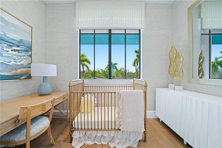 Bedroom with radiator heating unit, a nursery area, and wood finished floors