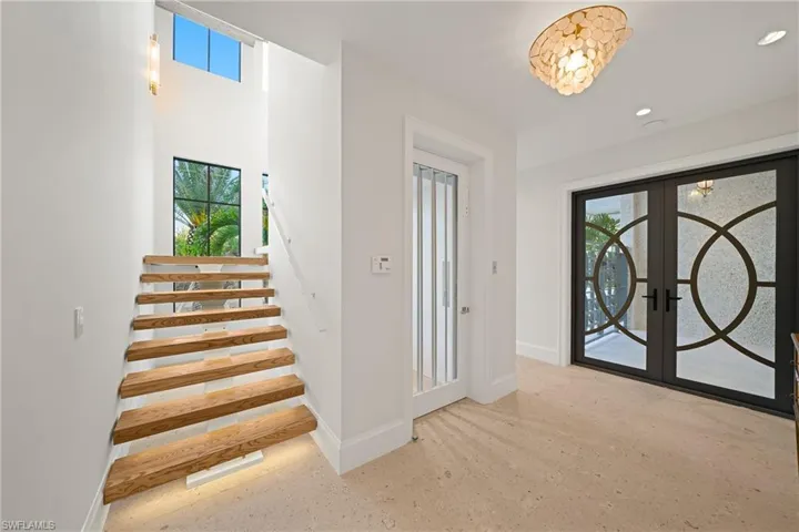 Foyer entrance featuring healthy amount of natural light, french doors, and stairs