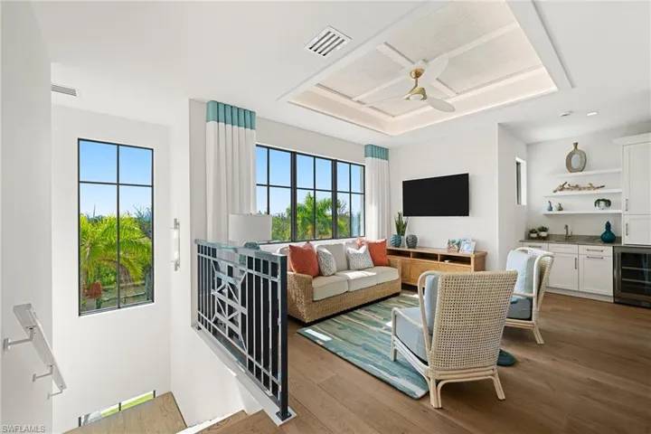 Living room with beverage cooler, wet bar, wood-type flooring, and a ceiling fan