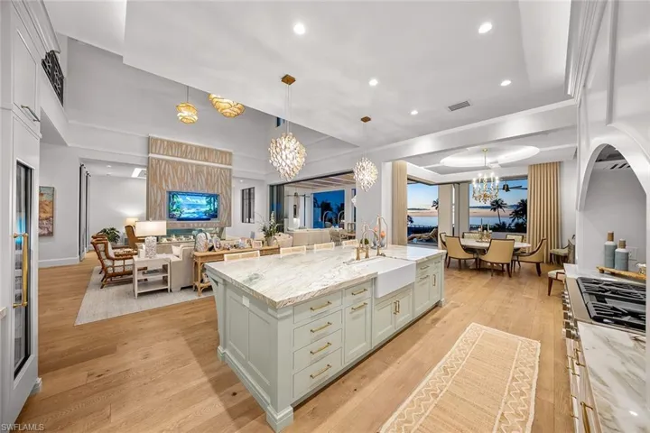 Kitchen featuring light stone countertops, open floor plan, a chandelier, pendant lighting, and recessed lighting