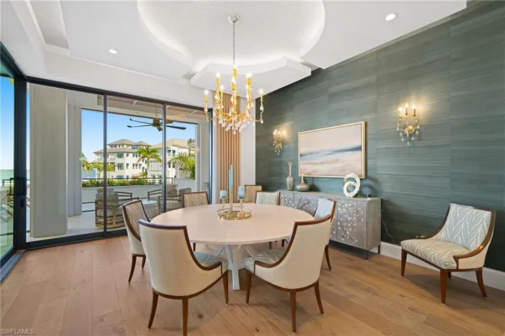 Dining room with an accent wall, wood-type flooring, ceiling fan, wallpapered walls, and a chandelier
