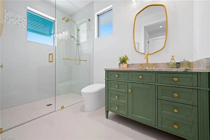 Full bath featuring vanity, a walk in shower, plenty of natural light, and light tile patterned flooring