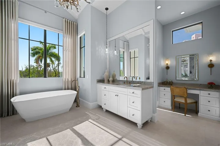 Bathroom featuring a chandelier, vanity, a soaking tub, and healthy amount of natural light