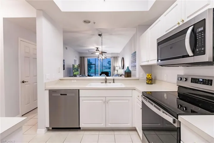 Kitchen with ceiling fan, light tile floors, sink, white cabinetry, and appliances with stainless steel finishes