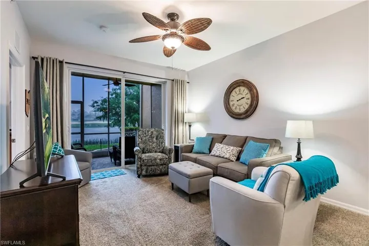 Carpeted living room featuring a water view and ceiling fan