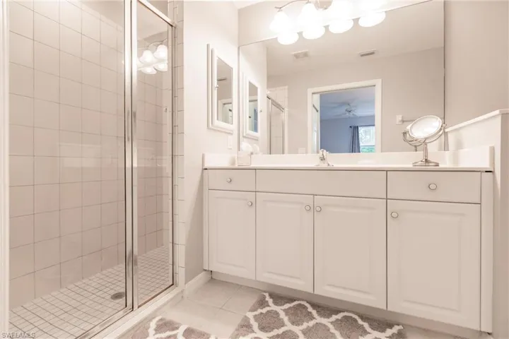 Bathroom with walk in shower, tile flooring, vanity, and ceiling fan