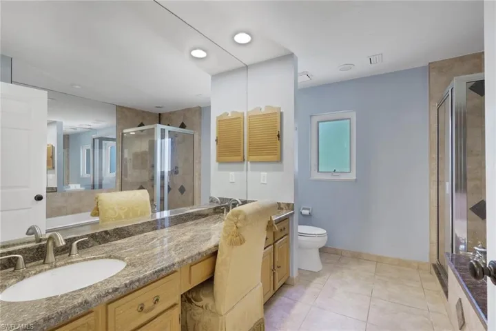 Bathroom featuring vanity, a stall shower, light tile patterned flooring, and a garden tub