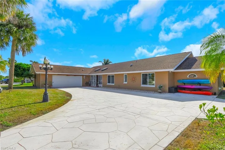 Ranch-style house with stucco siding, concrete driveway, a front yard, a garage, and roof with shingles
