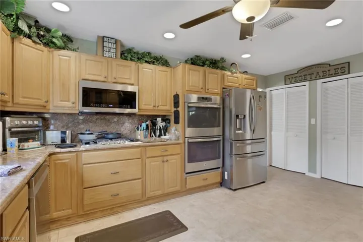 Kitchen featuring light wood finish cabinetry, stainless steel appliances, a ceiling fan, tasteful backsplash, and recessed lighting