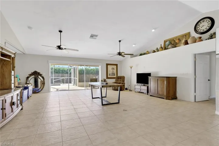 Living area featuring lofted ceiling, ceiling fan, and light tile patterned flooring