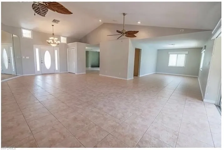 Unfurnished living room with ceiling fan, light tile patterned flooring, a high ceiling, and suspended lighting