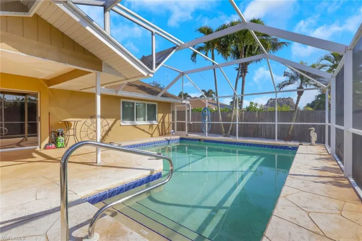 View of swimming pool featuring a sunroom, patio surround, and a lanai