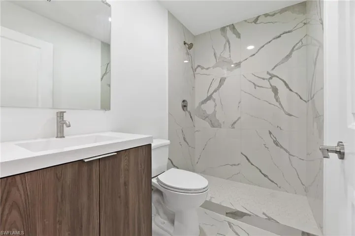 Full bath with toilet, marble finish floor, vanity, and a marble finish shower