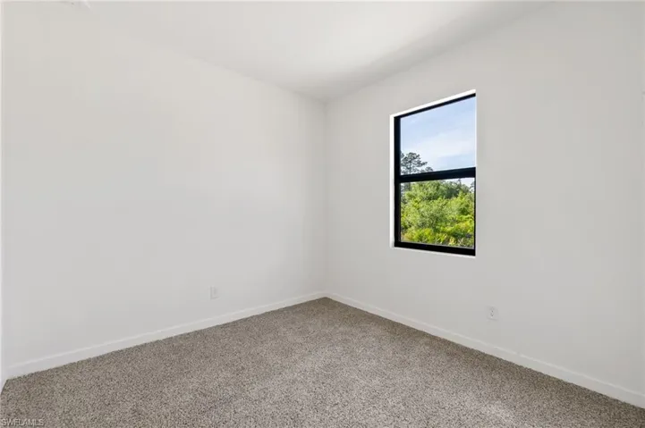 Spare room featuring light carpet and baseboards