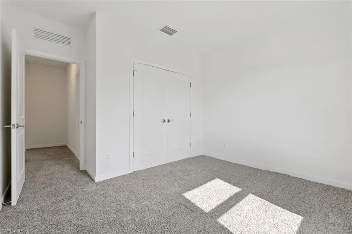 Unfurnished bedroom with baseboards, carpet floors, a closet, and visible vents