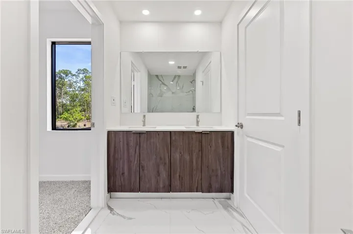 Bathroom with marble finish floor, a marble finish shower, baseboards, and a sink