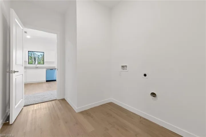 Laundry area featuring laundry area, light wood-style flooring, electric dryer hookup, washer hookup, and baseboards