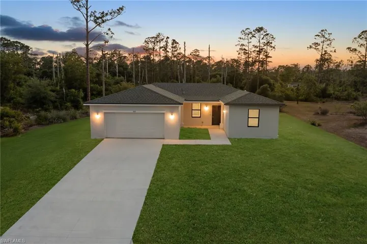 View of front of home featuring driveway, a garage, stucco siding, and a front yard