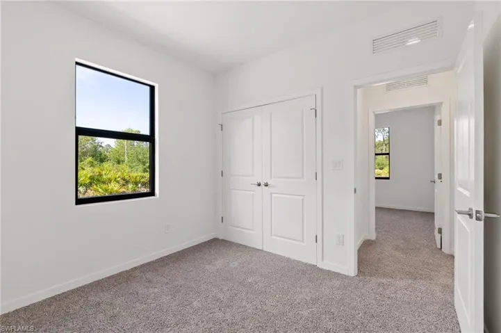 Unfurnished bedroom featuring baseboards, carpet flooring, a closet, and visible vents