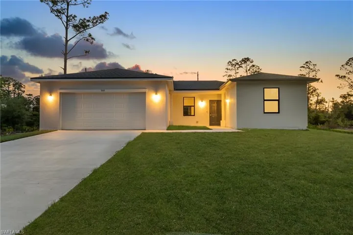 Ranch-style house featuring concrete driveway, a garage, stucco siding, and a front yard