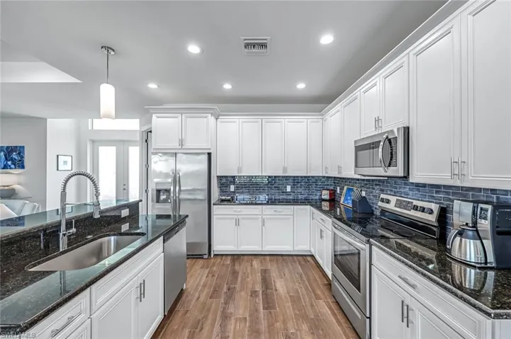 Kitchen with appliances with stainless steel finishes, a sink, white cabinetry,