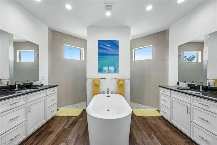 Bathroom with a walk in shower, two vanities, and tile walls
